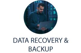 Data Recovery & Backup - male technician using laptop with server racks in background