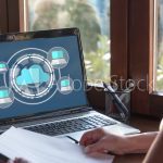 woman using a laptop computer with rendering of computer icons and cloud infrustructure